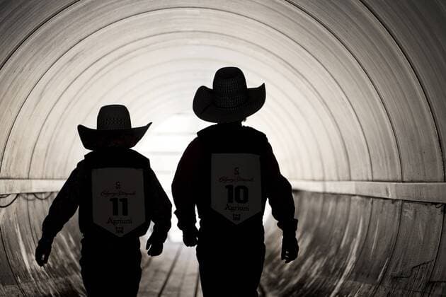Calgary, Alberta; Canada--- Two very young rodeo cowboys walk through a pedestrian tunnel as the go to compete in the Wild Pony Race event during the rodeo at Calgary Stampede. digital photo by Larry MacDougal