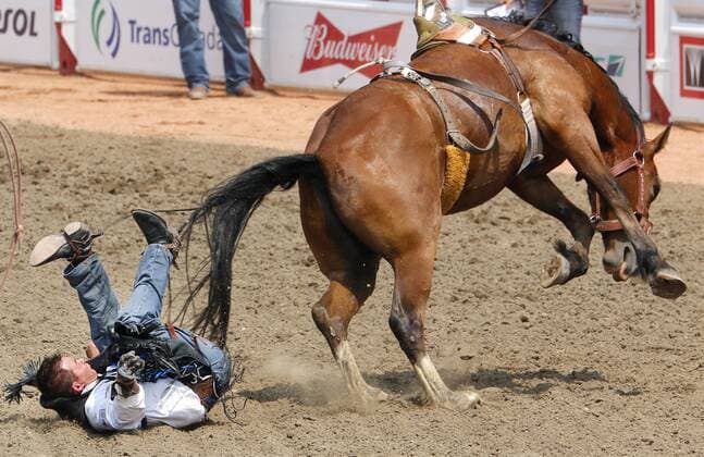 Calgary, Alberta; Canada--- Young cowboy Wyatt Gleeson (from Sundre, Alberta) is bucked off a horse called Xotic Departure in the Novice Bareback Riding event during the rodeo at Calgary Stampede. digital photo by Larry MacDougal