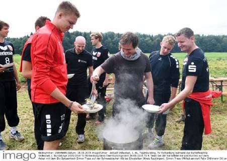 Aktuell Volleyball, 1. BL, Teambuilding, TV Rottenburg während der Kartoffelernte Volleyball 1. Bundesliga 2015 2016 TV Rottenburg beim Teambuildingevent 24.08.2015 TV R Team bei der Kartoffelernte und Kochen auf dem Acker mit dem Bio Spitzenkoch Simon Tress auf der Schwaebischen Alb bei Ehestetten (Kreis Reutlingen). Simon Tress (Mitte) serviert Felix Orthmann (li) und Co-Trainer Karsten Haug den Eintopf 