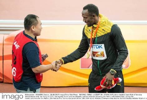 BEIJING, CHINA - AUGUST 28: (CHINA OUT) Gold medalist Usain Bolt of Jamaica shakes hands with Tao Song of CCTV, the segway driver who accidentally collided with him following the Men s 200 metres final, during the medal ceremony for the Men s 200 metres final during day seven of the 15th IAAF World Athletics Championships Beijing 2015 at Beijing National Stadium on August 28, 2015 in Beijing, China.  CFP471986730 
