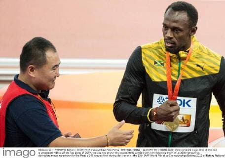 BEIJING, CHINA - AUGUST 28: (CHINA OUT) Gold medalist Usain Bolt of Jamaica is presented with a gift by Tao Song of CCTV, the segway driver who accidentally collided with him following the Men s 200 metres final, during the medal ceremony for the Men s 200 metres final during day seven of the 15th IAAF World Athletics Championships Beijing 2015 at Beijing National Stadium on August 28, 2015 in Beijing, China.  CFP471986731 