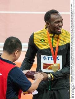 BEIJING, CHINA - AUGUST 28: (CHINA OUT) Gold medalist Usain Bolt of Jamaica is presented with a gift by Tao Song of CCTV, the segway driver who accidentally collided with him following the Men s 200 metres final, during the medal ceremony for the Men s 200 metres final during day seven of the 15th IAAF World Athletics Championships Beijing 2015 at Beijing National Stadium on August 28, 2015 in Beijing, China.  CFP471986734 