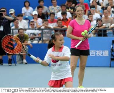 Retired Chinese tennis star Li Na, back, watches a young girl playing tennis in a master class during the 2015 WTA Tennis Damen Wuhan Open tennis tournament in Wuhan city, central China s Hubei province, 29 September 2015. Li Na plays up master class at WTA Wuhan Open  20150929_34417