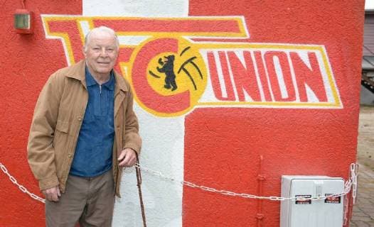 Fussball, Herren, Saison 2015 16, 2. Bundesliga, 1. FC Union Berlin, Feier zum 75. Geburtstag von Ehrenmitglied Günter Jimmy Hoge im Bootshaus Sportdenkmal in Berlin-Grünau, Hoge vor Union-Logo im Boots-Haus, 07.10. 2015,