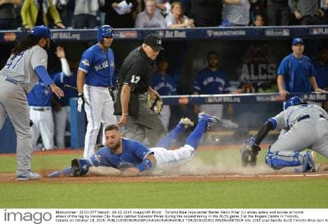 Toronto Blue Jays center fielder Kevin Pillar (L) slides safely and scores at home ahead of the tag by Kansas City Royals catcher Salvador Perez during the second inning in the ALCS game 3 at the Rogers Centre in Toronto, Canada on October 19, 2015.  TOR2015101911 KEVINxDIETSCH