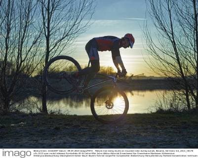 Mature man doing stunts on mountain bike during sunset, Bavaria, Germany mit_2013_00175