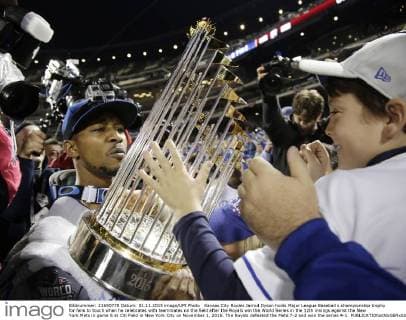 Kansas City Royals Jarrod Dyson holds Major League Baseball s championship trophy for fans to touch when he celebrates with teammates on the field after the Royals win the World Series in the 12th innings against the New York Mets in game 5 at Citi Field in New York City on November 1, 2015. The Royals defeated the Mets 7-2 and won the series 4-1.  NYP20151101178 JOHNxANGELILLO