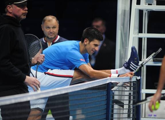 Tennis - 2015 ATP Tennis Herren World Tour Finals at The O2 - Pre-Tournament Media Day Novak Djokovic stretches his legs after training on the main court with Boris Becker 