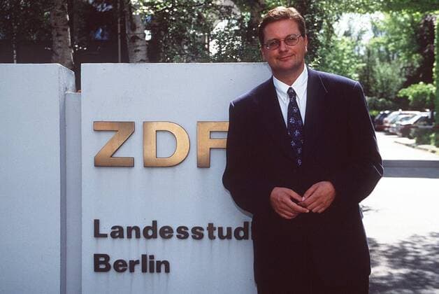 Reinhard Grindel (ZDF-Studioleiter Berlin) 08 97 te Mann Fernsehen TV Management Redaktion Jackett blau Anzug Krawatte Hemd Brille neutral seriös braunhaarig draußen halb quer stehend Logo ZDF Landesstudio Berlin People Shooting