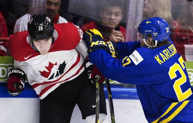 151231 Kanadas Roland McKeown blir tacklad av Sveriges Anton Karlsson under ishockeymatchen i junior-VM mellan Kanada och Sverige den 31 december 2015 i Helsingfors.  Copyright: JOELxMARKLUND BB151231JM040