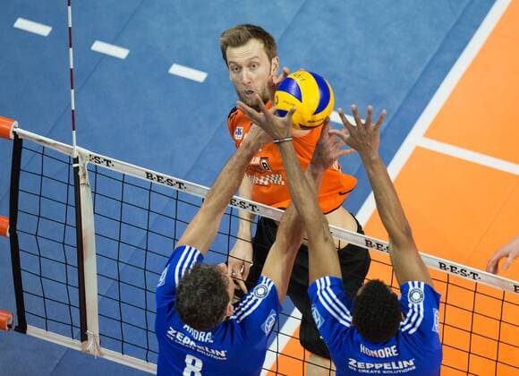 Berlin, Deutschland, 07.02.2016: Volleyball Bundesliga Saison 2015 2016 - Berlin Recycling Volleys - VfB Friedrichshafen. Paul Carroll (BR Volleys 12) gegen den Block aus Björn Bjoern Andrae (VfB Friedrichshafen 8) und Marc-Anthony Honore (VfB Friedrichshafen 9)