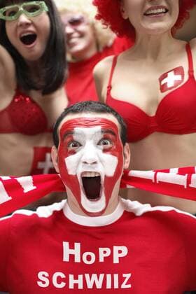 Schreiender junger Mann, Fußballfan, mit Gesichtsbemalung mit schweizerischer Nationalflagge und Shirt mit Aufschrift Hopp Schwiiz iblart02220632.jpg