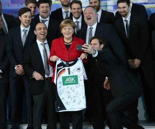 GER, Handball Nationalmannschaft zum Besuch bei Kanzlerin Angela Merkel 09.03.2016, Bundeskanzleramt, Berlin, GER, Handball Nationalmannschaft zum Besuch bei Kanzlerin Angela Merkel, im Bild Andreas Michelmann ( DHB-Praesident ), Trikot mit dem Namen der Kanzlerin, Manager Bob Hanning (Fuechse Berlin), Uwe Gensheimer macht Selfis Fabian Wiede (Fuechse Berlin) nphxEngler