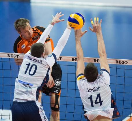 Berlin, Deutschland, 12.04.2016: Volleyball Bundesliga Saison 2015 2016 Playoff-Halbfinale Spiel 1 - Berlin Recycling Volleys - SVG Lueneburg Lüneburg. Paul Carroll (BR Volleys 12) gegen den Block aus Steven Marshall (Lüneburg 10) und Michel Schlien (Lüneburg 14)