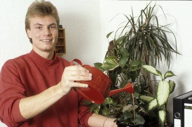Thomas Helmer (Fußballspieler) 05 89 ru Thomas Helmer im Mai 1989 Deutschland deutsch deutscher Mann Fußball Fußballer Bundesliga privat Homestory german soccer player quer halb stehend lächelnd Blumen gießen gießend blumengießend Pflanzen Gießkanne Hobbygärtner Pflanze
