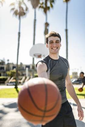 Smiling young man holding basketball on outdoor court model released Symbolfoto  LEF000103