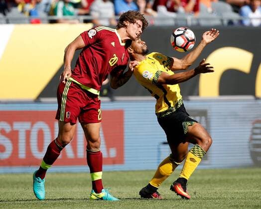 Venezuela defender Rolf Feltscher (L) and Jamaica forward Garath McCleary go for the ball during the first half of a 2016 Copa America Centenario Group C match at Soldier Field in Chicago on June 5, 2016.  CHI2016060510 BRIANxKERSEY