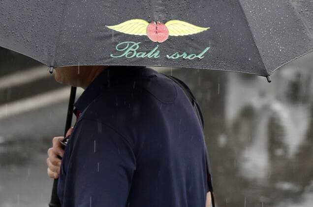 A man holds a Baltusrol umbrella in the rain before play is suspended due to rain in the 3rd round at the PGA Golf Herren Championship at Baltusrol Golf Club in Springfield, New Jersey on July 30, 2016.  PGA20160730118 JOHNxANGELILLO