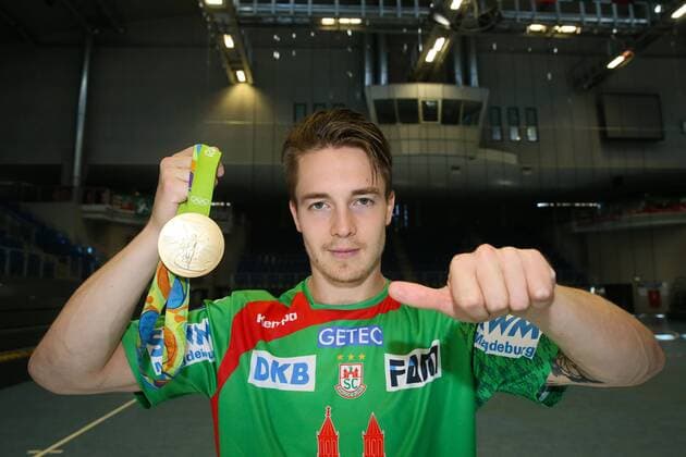 Themen der Woche - SPORT Bilder des Tages - SPORT Handball, 1. BL, SC Magdeburg Porträttermin Michael Damgaard (SC Magdeburg) mit seiner olympischen Goldmedaille von Rio - Handball Bundesliga Saison 2016-2017 Offizeller Fototermin SC Magdeburg in der GETEC Arena in Magdeburg - Einzelbild,Portrait,Deutschland, Handball, Mann, Maenner,25.08.2016