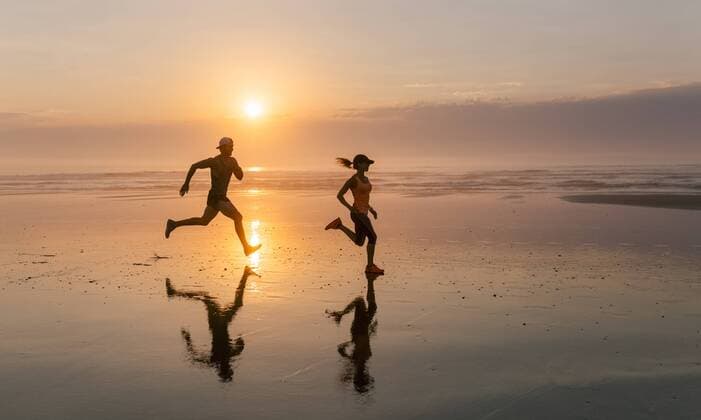Athletes couple running on the beach at sunset model released Symbolfoto  MGOF002146