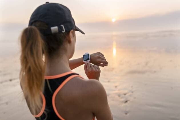 Young athlete woman looking the smartwatch on the beach at sunset model released Symbolfoto  MGOF002155
