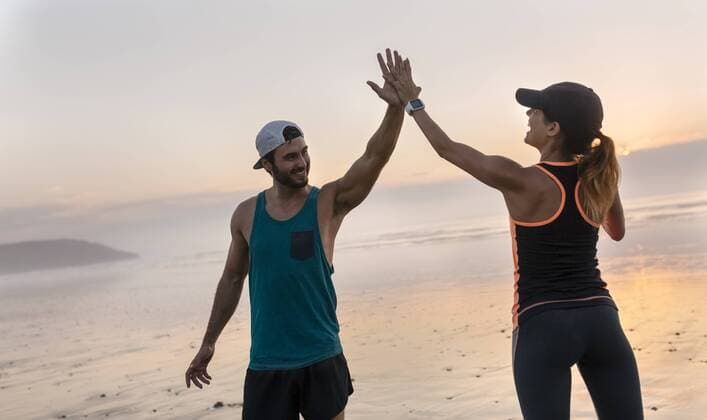 Athletes couple hitting five on the beach at sunset model released Symbolfoto  MGOF002157