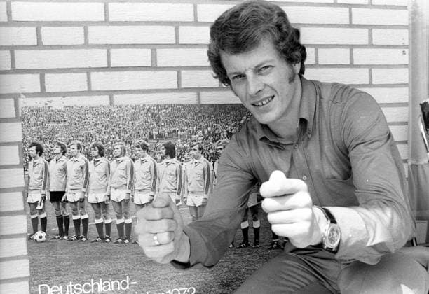 Herbert -Hacki- Wimmer (BR Deutschland Borussia Mönchengladbach) drückt vor einem Poster mit Mannschaftsfoto von Europameister Deutschland die Daumen