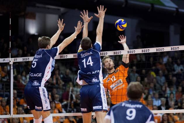Berlin, Deutschland, 30.10.2016: Volleyball Bundesliga Saison 2016 2017 - Berlin Recycling Volleys - SVG Lueneburg. Paul Carroll (BR Volleys 12) gegen den Block aus Cody Kessel (Lüneburg 5), Michel Schlien (Lüneburg 14)