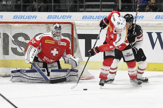 Eishockey Deutschland Cup 2016: Kanada vs Schweiz am 04.11.2016 im Curt-Frenzel-Stadion in Augsburg Schweiz™ Patrick Geering 4 ZSC Lions (NLA) gegen Kanadas Paul Szczechura 12 Traktor Chelyabinsk (KHL) neben dem Tor von Schweiz™ Goalie Tobias Stephan 52 EV Zug (NLA) WD