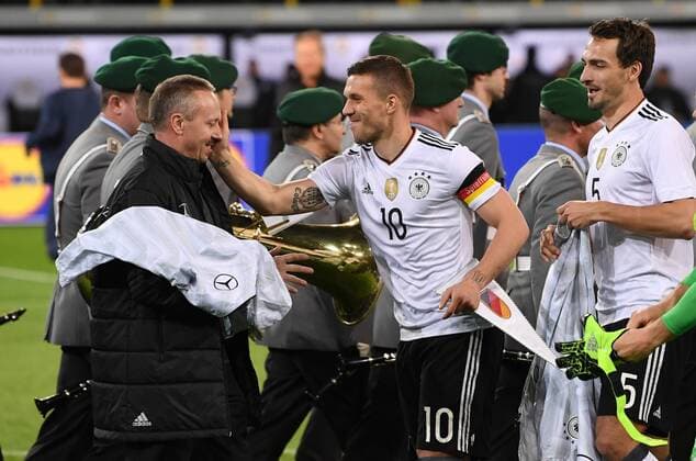 FUSSBALL INTERNATIONAL TESTSPIEL IN DORTMUND 22.03.2017 Deutschland - England Lukas Podolski (Mitte) watscht Chef-Zeugwart Thomas Mai (Mitte) ab. Mats Hummels (re, alle Deutschland) ist amuesiert 