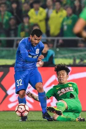 Argentine football player Carlos Tevez of Shanghai Shenhua, left, passes the ball against a player of Beijing Guoan in their third round match during the 2017 Chinese Football Association Super League (CSL) in Beijing, China, 2 April 2017. Beijing Guoan defeated Shanghai Shenhua 2-1 at 3rd round of 2017 Chinese Super League. Beijing Guoan edges out Shanghai Shenhua at 3rd round of 2017 CSL  20170402_63317