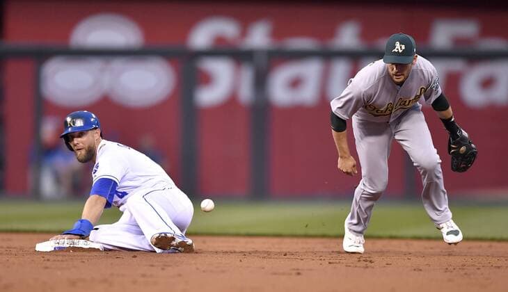 April 12, 2017 - Kansas City, MO, USA - Oakland Athletics second baseman Jed Lowrie, right, chases after the ball as the Kansas City Royals Alex Gordon reaches second on a single by Lorenzo Cain in the first inning at Kauffman Stadium in Kansas City, Mo., on Wednesday, April 12, 2017. Oakland at Kansas City - ZUMAm67_ 20170412_zaf_m67_008 Copyright: xJohnxSleezerx