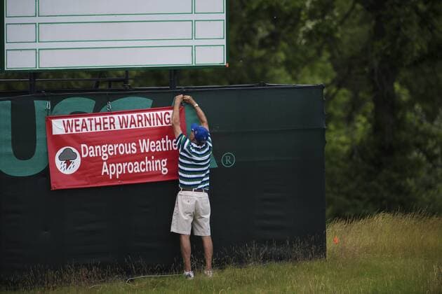 170614 En funktionär sätter upp en skylt som varnar för ett oväder som drar in över golfbanan Erin Hills inför golfturneringen US Open den 14 juni 2017 i Hartford.  Copyright: JOELxMARKLUND BB170614JM031
