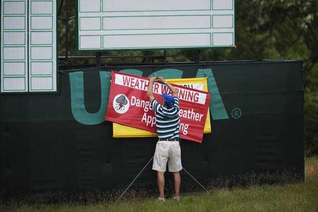 170614 En funktionär sätter upp en skylt som varnar för ett oväder som drar in över golfbanan Erin Hills inför golfturneringen US Open den 14 juni 2017 i Hartford.  Copyright: JOELxMARKLUND BB170614JM034