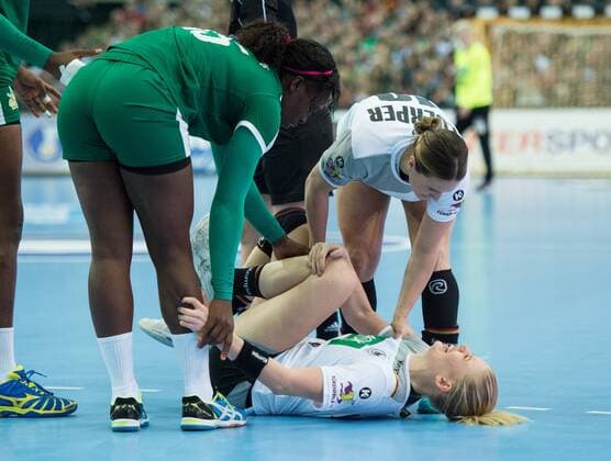 Kim Naidzinavicius 15 GER is down and touches her left knee after a game scene with Yvette Yuoh 5 CMR and Anne Michelle Essam 15 CMR Anna Loerper 10 GER is in her preliminary group match Germany Cameroon in Leipzig on 01 12 2017 Handball 23 Womens Handball World Cup in Germany 2017