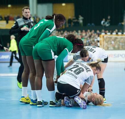 Kim Naidzinavicius 15 GER is down and touches her left knee after a game scene with Yvette Yuoh 5 CMR and Anne Michelle Essam 15 CMR Anna Loerper 10 GER and Angie Geschke 26 GER are in their preliminary group match Germany Cameroon in Leipzig on 01 12 2017 Handball 23 Women Handball World Cup in Germany 2017