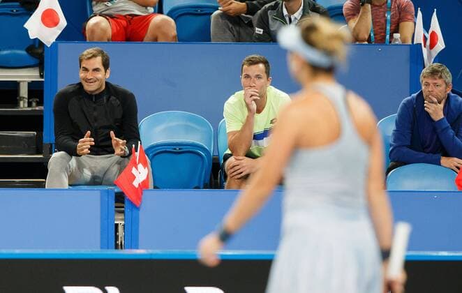 ROGER FEDERER sitting laughing in the players box and shows BELINDA BENCIC that was blurred in the foreground their ball in the right coach Ian Hughes mixed doubles Copyright: xJuergenxHasenkopfx