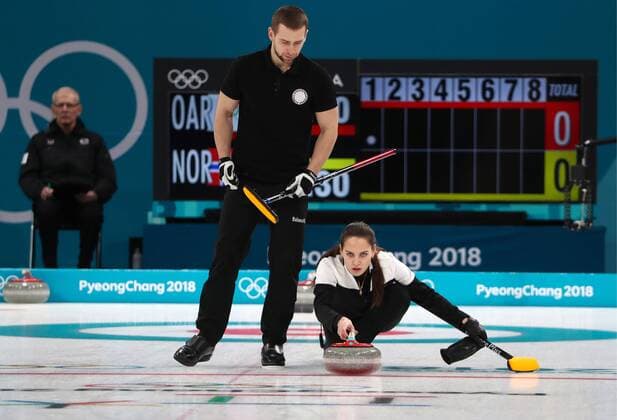 GANGNEUNG, SOUTH KOREA â€“ FEBRUARY 13, 2018: Curler Alexander Krushelnitsky (L) looks on as Anastasia Bryzgalova, Olympic Athletes from Russia, delivers a stone in their mixed doubles curling bronze medal match against Norway s Kristin Skaslien and Magnus Nedregotten during the 2018 Winter Olympic Games Olympische Spiele Olympia OS at the Gangneung Curling Centre. Olympic Athletes from Russia won the game 8:4. Valery Sharifulin TASS  TS0738B1