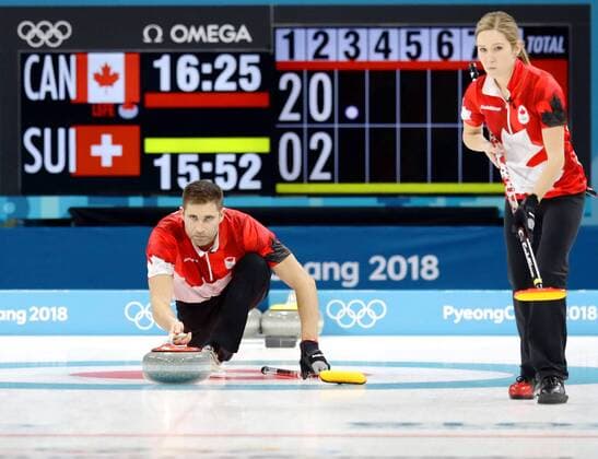 Pyeongchang Olympics John Morris (L) of Canada delivers a stone, with teammate Kaitlyn Lawes looking on, in the third end of the curling mixed doubles final against Switzerland at the Pyeongchang Winter Olympics in Gangneung, South Korea, on Feb. 13, 2018. 