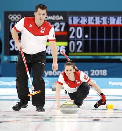 Pyeongchang Olympics Jenny Perret (R) delivers a stone as Swiss teammate Martin Rios looks on in the third end of the curling mixed doubles final against Canada at the Pyeongchang Winter Olympics in Gangneung, South Korea, on Feb. 13, 2018. 