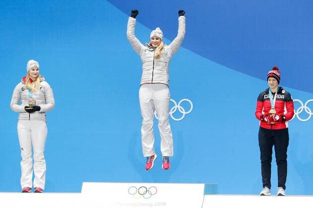 Women s Singles Luge gold medalist Natalie Geisenberger of Germany (C) leaps on the podium at the medals ceremony for the 2018 Pyeongchang Winter Olympics at the Pyeongchang Medals Plaza in Pyeongchang, South Korea, on February 14, 2018. At left is silver medalist Dajana Eitberger of Germany and bronze medalist Alex Gough of Canada at right.  OLY20180214131 MATTHEWxHEALEY