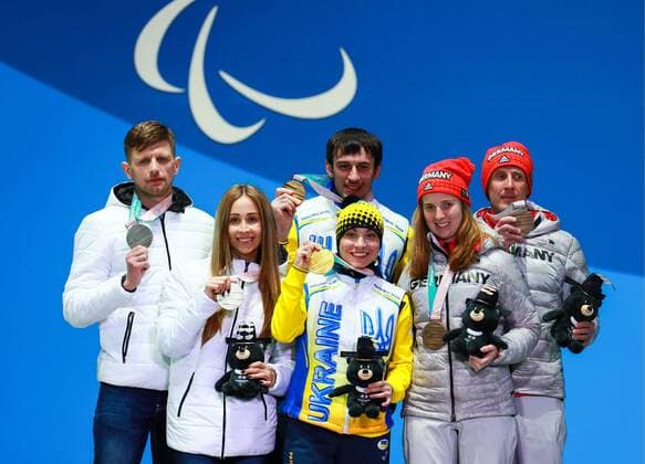 PYEONGCHANG, SOUTH KOREA - MARCH 13, 2018: Second-placed neutral Paralympic athlete (NPA) from Russia Mikhalina Lysova (2nd L) guided by Alexei Ivanov, first-placed Oskana Shyshkova (C front) guided by Vitaly Kazakov of Ukraine, and third-placed Clara Klug (R front) guided by Martin Hartl of Germany pose at a ceremony to award the visually impaired women s 10km biathlon race winners at the 2018 Winter Paralympic Games. Vladimir Smirnov TASS  TS07772D