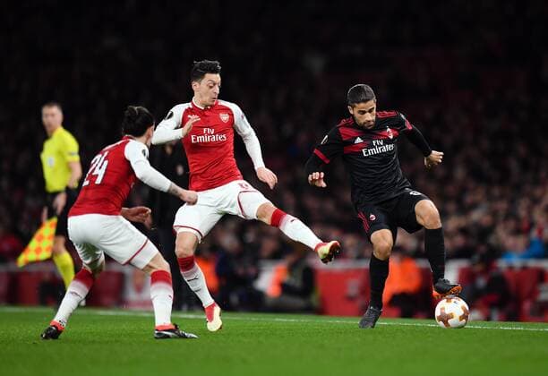 Football - 2017 2018 UEFA Europa League - Round of Sixteen, Second Leg: Arsenal (2) vs. AC Milan (0) AC Milan™s Ricardo Rodriguez holds off the challenge from Arsenal s Mesut Ozil COLORSPORT ASHLEY WESTERN 