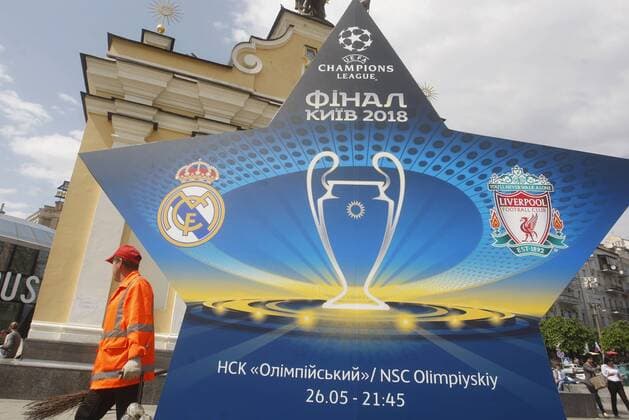 May 12, 2018 - Kiev, Ukraine - A municipal worker walks past a large sign showcasing the logo for the 2018 UEFA Champions League Final in Kiev, Ukraine, 12 May, 2018. Kiev is preparing for the 2018 UEFA Champions League Final which will be played at the NSC Olimpiyskiy Stadium on May 26, 2018 and for the 2017-18 UEFA Women s Champions League final which will be played at Valeriy Lobanovskiy Dynamo Stadium on 24 May. 2018 UEFA Champions League Final in Kiev  - ZUMAn230 20180512_zaa_n230_571 Copyright: xStrx