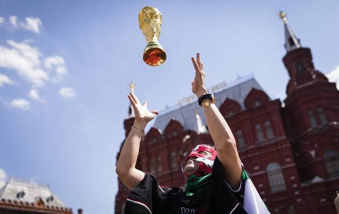 Moscow 17 06 2018 Mexican fan throws World Cup trophy in Germany colors in front of the State Historical Museum Moscow in the air land and people