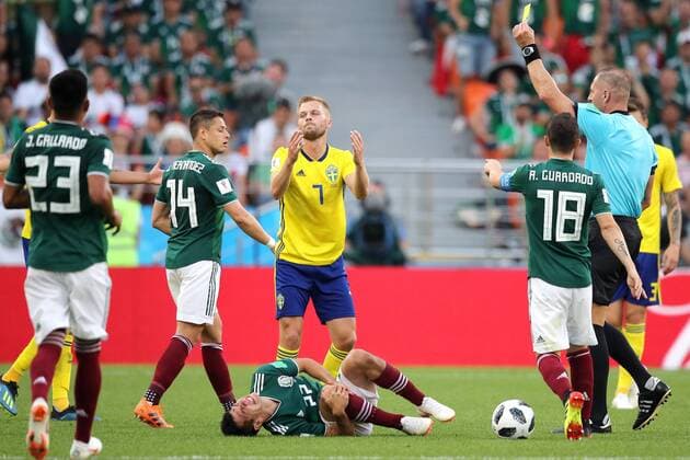 YEKATERINBURG, RUSSIA - JUNE 27, 2018: Mexico s Hirving Lozano (C front), Sweden s Sebastian Larsson (C background), who has received a yellow card, and referee Nestor Pitana (R) in the 2018 FIFA World Cup WM Weltmeisterschaft Fussball First Stage Group F football match between Mexico and Sweden at Ekaterinburg Arena Stadium. Sergei Bobylev TASS  TS086AC4
