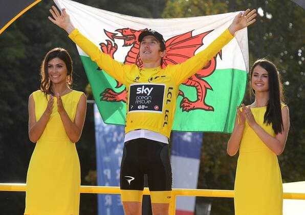 British Geraint Thomas of Team Sky wearing the yellow jersey of overall leader and holding a Welsh flag celebrates on the podium after the last stage of the 105th edition of the Tour de France cycling race, 116km from Houilles to Paris, France, Sunday 29 July 2018. This year s Tour de France takes place from July 7th to July 29th. DAVIDxSTOCKMAN  x05395119x