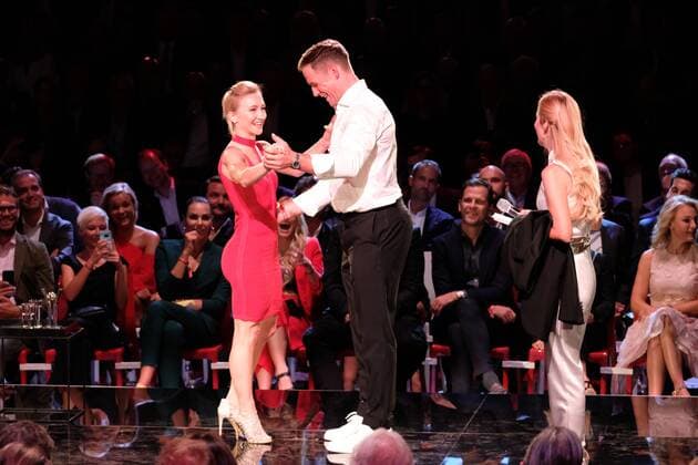 Laureate Aljona Savchenko and a hockey player try a lifting figure right Moderator Andrea Kaiser Presentation of the Sport Bild Award at the fish auction hall Große Elbstraße in Hamburg on 27 8 2018