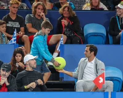 Roger Federer sits in the players box and writes an autograph for a boy from Stefanos Tsitsipas Team Copyright: xJuergenxHasenkopfx