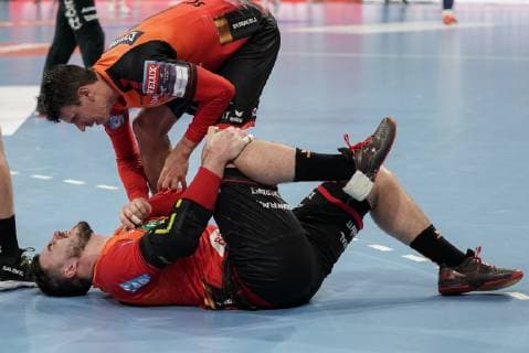 Andre Schmid Andy Schmid RNL 2 takes care of Jannik Kohlbacher RNL 80 who holds his right knee in pain after a foul racked with pain injured injury injured sporting injury action scene handball champions league Rhein Neckar lions PGE Vive Kielce xozx